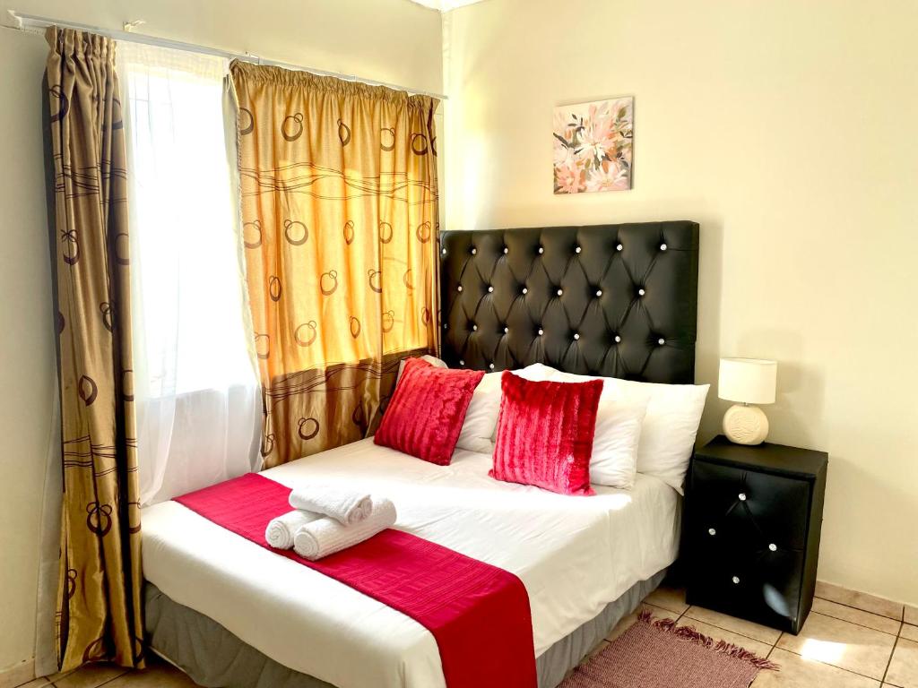 a bedroom with a bed with red and white pillows at 2 Bedroom Apt Whk West in Windhoek