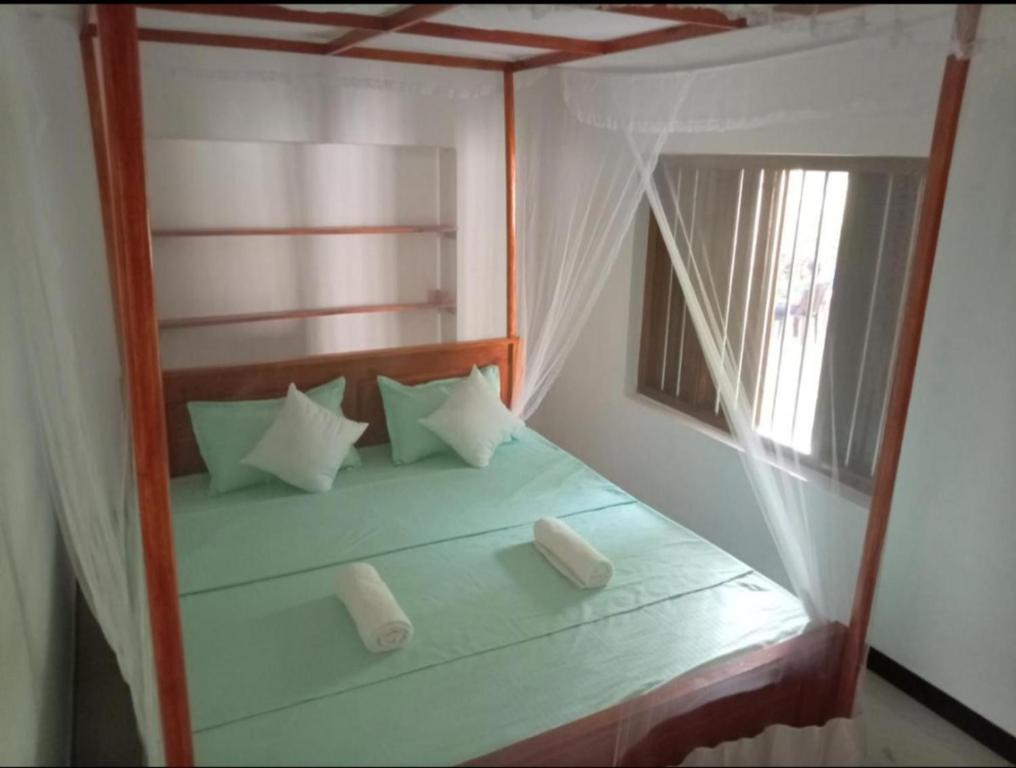 a bedroom with a canopy bed with a window at White Shell in Tangalle