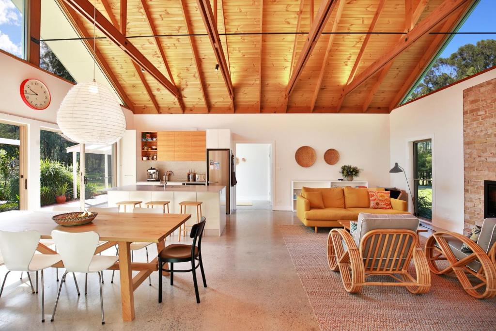 a dining room and living room with a wooden ceiling at The Paddock in Berry in Berry