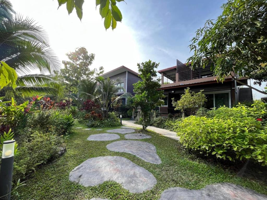 a garden with rocks in front of a house at BaanSuanklaiKlungBangkrachao บ้านสวนใกล้กรุงบางกะเจ้า in Phra Pradaeng