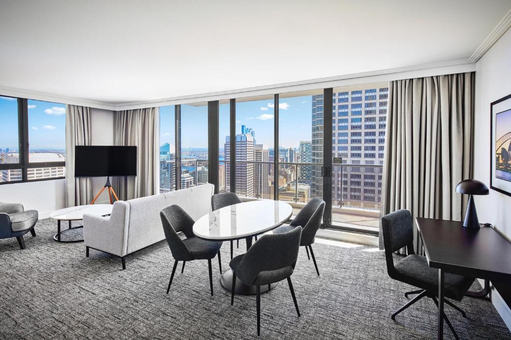 Habitación de hotel con mesa, sillas y ventana grande. en Meriton Suites Pitt Street, Sydney, en Sídney