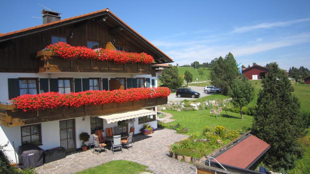 ein Gebäude mit roten Blumen auf der Seite in der Unterkunft Landhaus Suntheim in Wertach