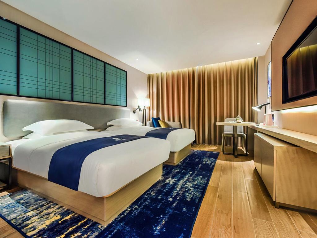 a hotel room with two beds and a television at Yishang Hotel Anshun High-speed Railway Station Airport Road Branch in Anshun