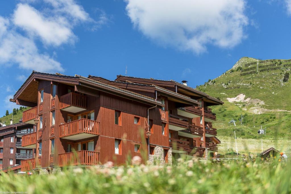 a brown building with a mountain in the background at Résidence Pierre &amp; Vacances Emeraude in Belle Plagne