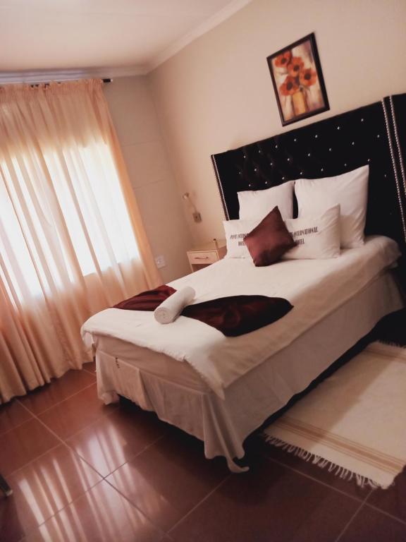 a bedroom with a large bed with white pillows at Punyu International Hotel in Khomas Region
