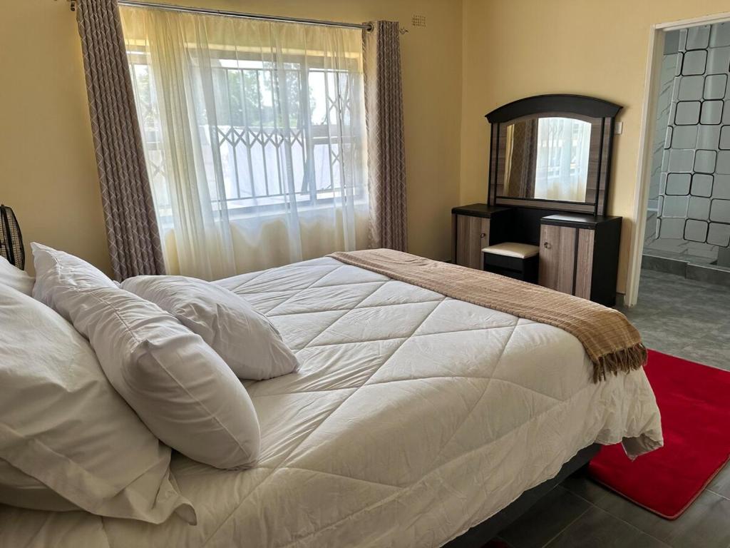ein Schlafzimmer mit einem großen weißen Bett mit einem Fenster in der Unterkunft Hatfield staylax Manor 1 in Harare