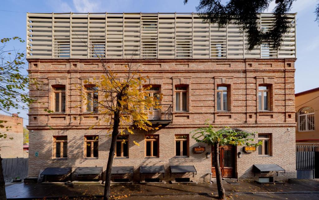 Un gran edificio de ladrillo con bancos delante. en Magnolia, en Tiflis