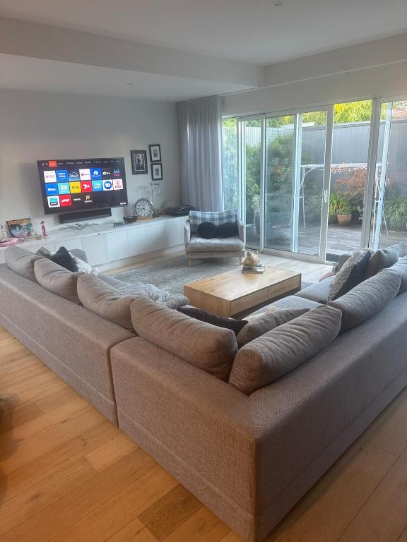 a large couch in a living room with a television at Inner city quiet cottage in Melbourne