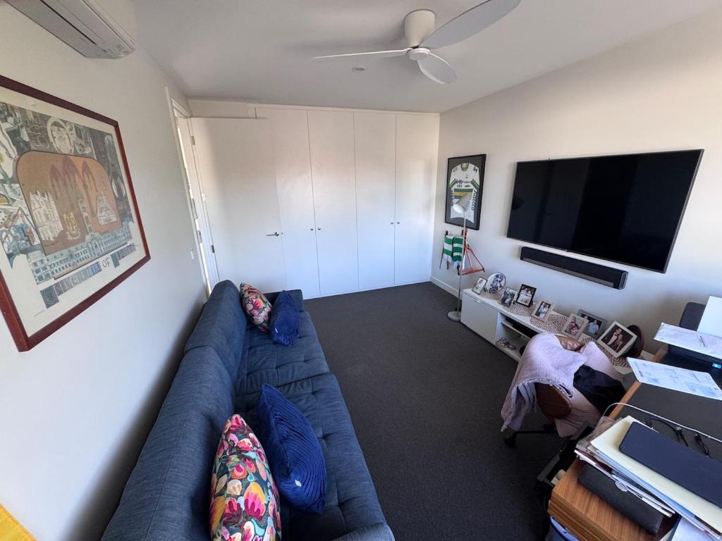 a living room with a blue couch and a flat screen tv at Inner city quiet cottage in Melbourne