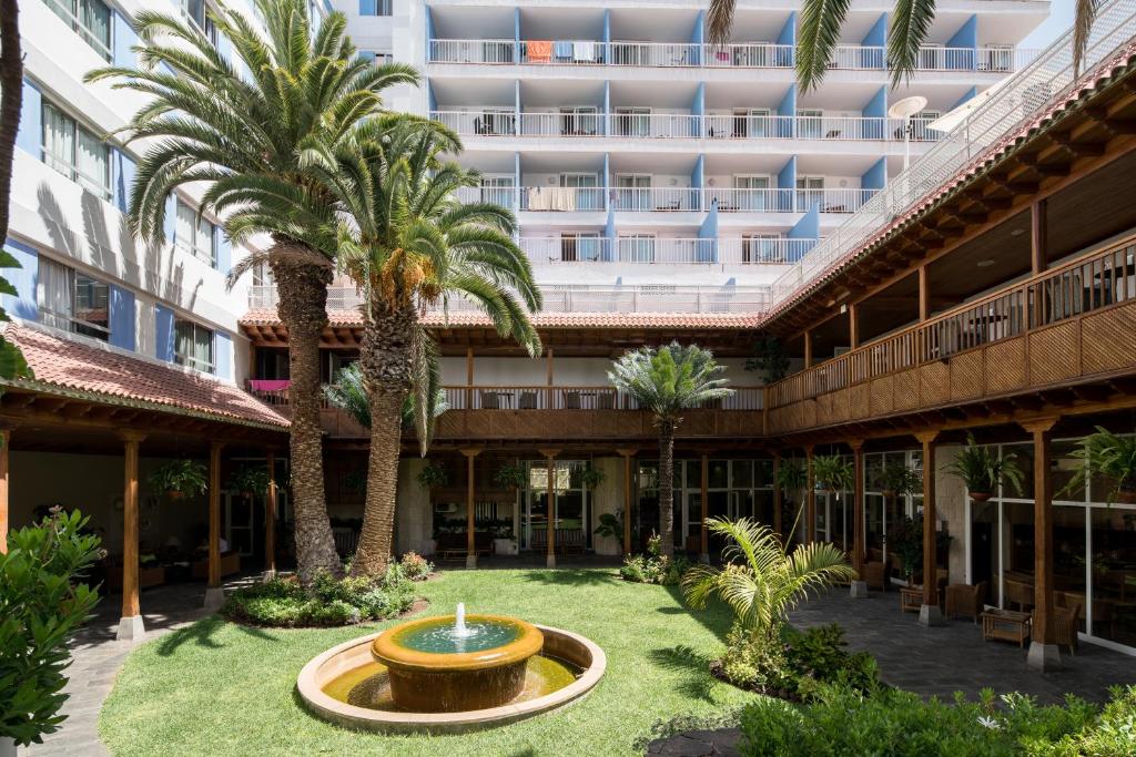 une cour avec une fontaine et des palmiers devant un bâtiment dans l'établissement Catalonia Las Vegas - Adults Only, à Puerto de la Cruz