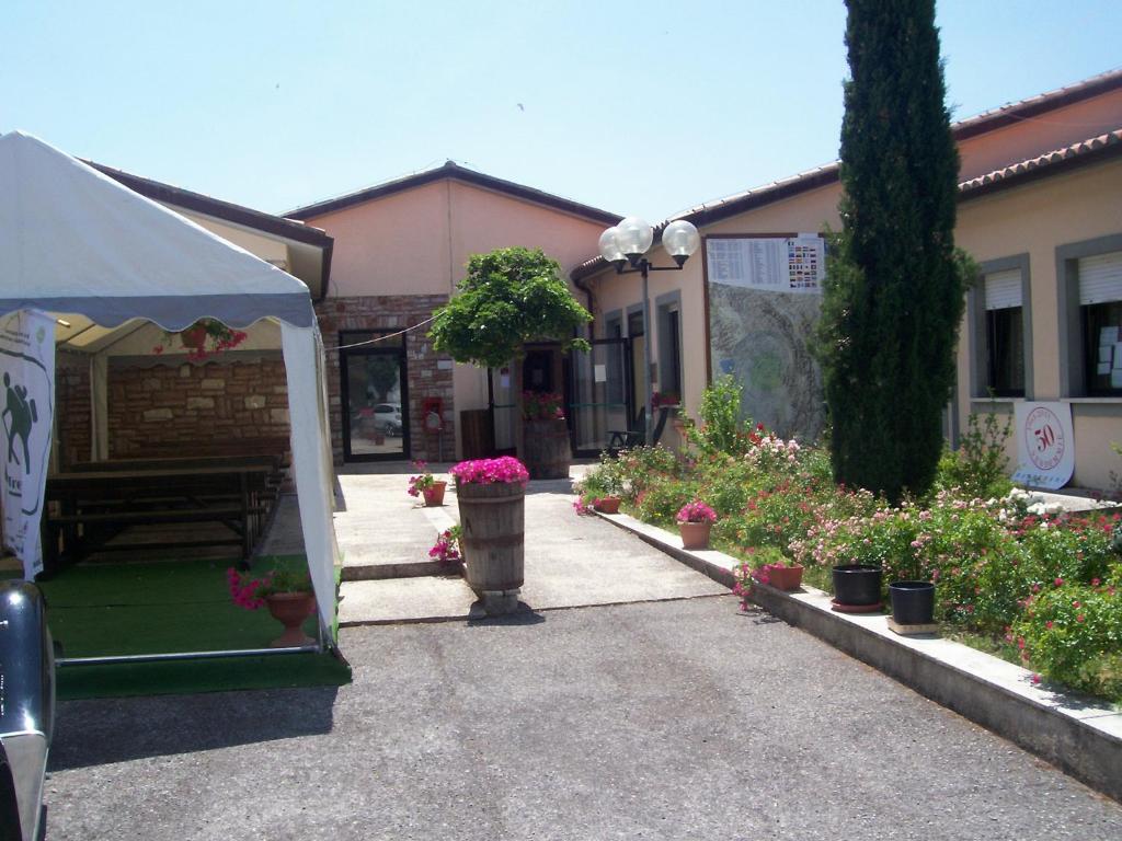 a tent is set up in a courtyard with flowers at Ostello Del Volo in Sigillo