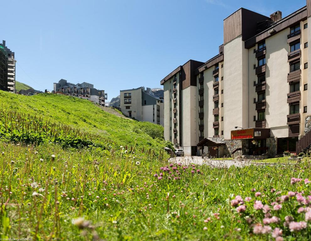 a green hill with buildings and a field of flowers at Résidence Pierre & Vacances Inter-Résidences in Tignes