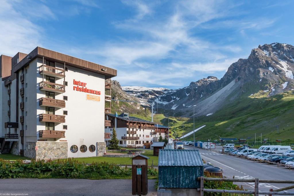a hotel with a parking lot and a mountain at Résidence Pierre & Vacances Inter-Résidences in Tignes