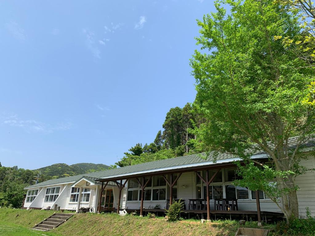 a white house with a tree in front of it at 里山のいぶき舎 in Goto