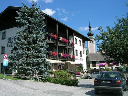 ein Auto, das vor einem Gebäude mit einem Weihnachtsbaum parkt in der Unterkunft Gasthof-Pension Golob in Kirchbach