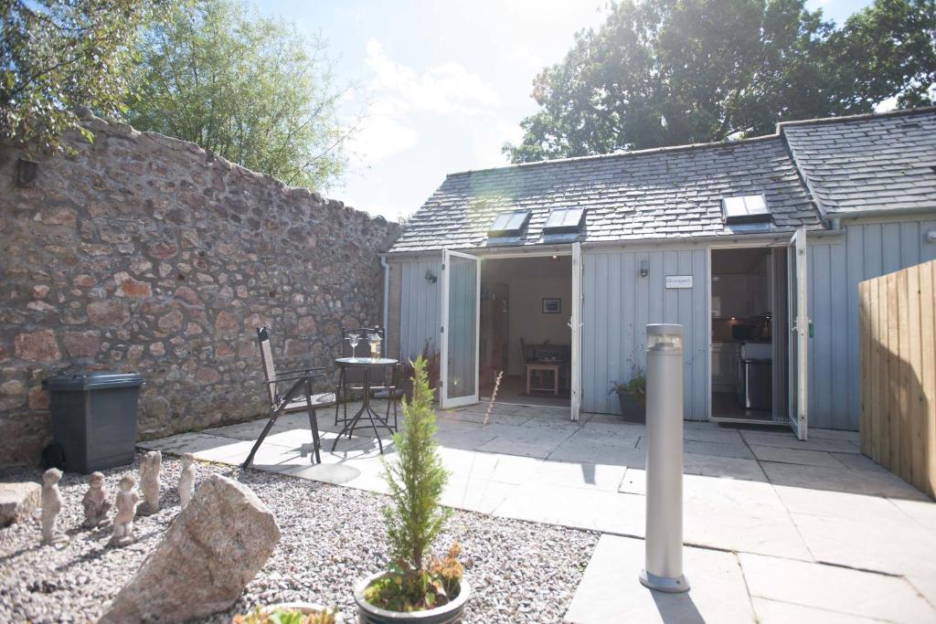 a garden with a building and a stone wall at Glenernan Self Catering Cottages in Ballater