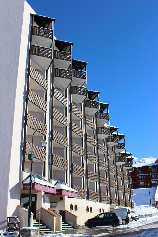 a building in the snow with a car parked in front at Temples Du Soleil Tikal Appartements VTI in Val Thorens