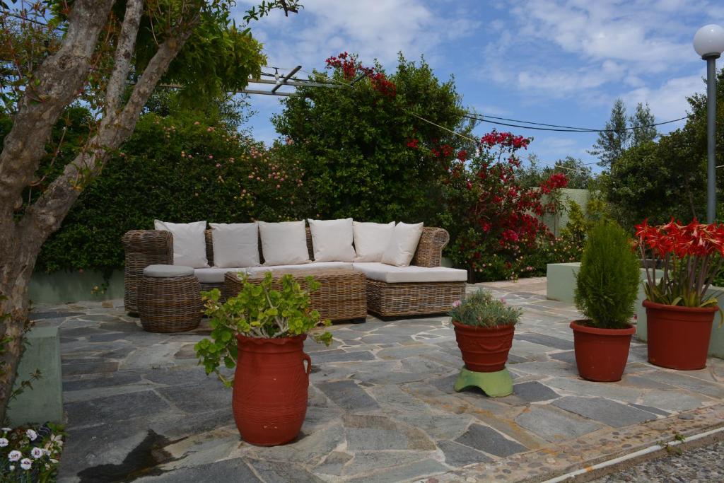 un divano seduto su un patio in pietra con piante in vaso di Varkiza's Cottages a Varkiza