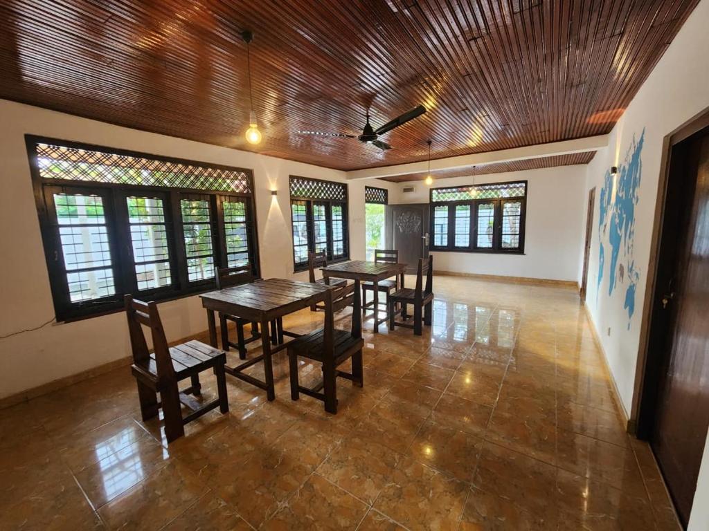 a dining room with tables and chairs and windows at Ryo hostel in Ahangama