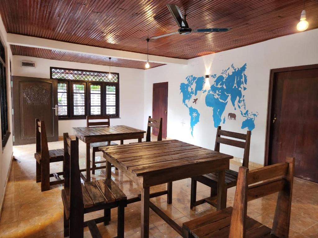 Un comedor con mesas y sillas y un mapa del mundo en la pared. en Ryo hostel, en Ahangama