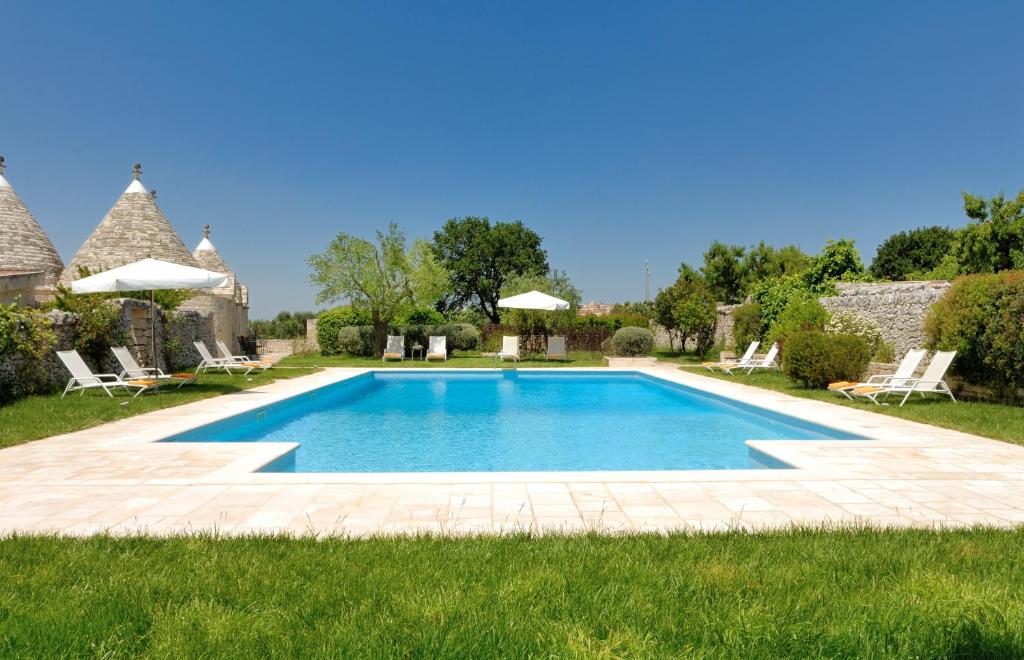 una piscina in un cortile con sedie e ombrelloni di Abate Masseria & Resort a Noci