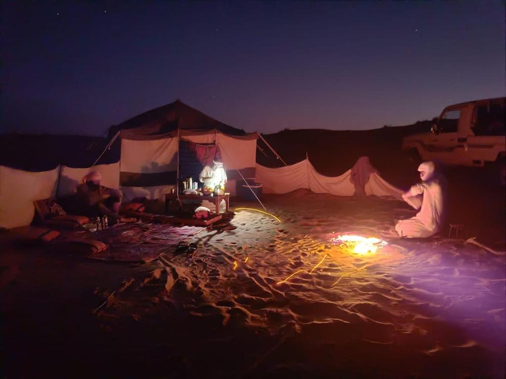 un grupo de personas sentadas en una tienda por la noche en EXPIORER Desert Camp, en Al Raka