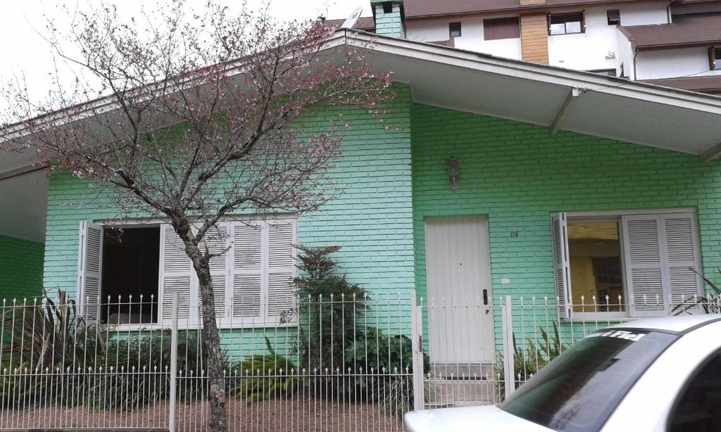 una casa verde con una valla delante en Casa Rua Padre Carmene, en Gramado
