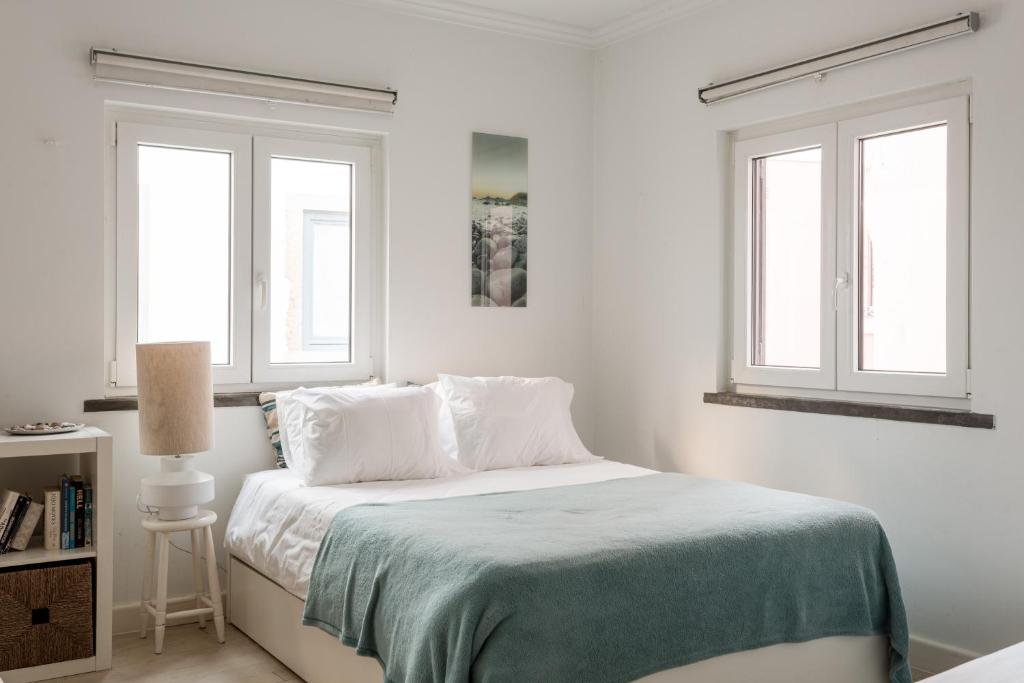 Un dormitorio blanco con una cama y dos ventanas. en Lisbon Apartments by Propr, en Cascais