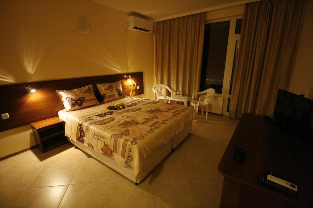 a bedroom with a large bed and a table and chairs at Hotel Marant in Sozopol