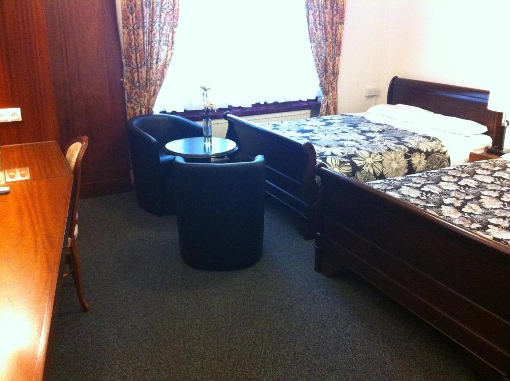 a hotel room with two beds and a table and chairs at London Visitors Hotel in London