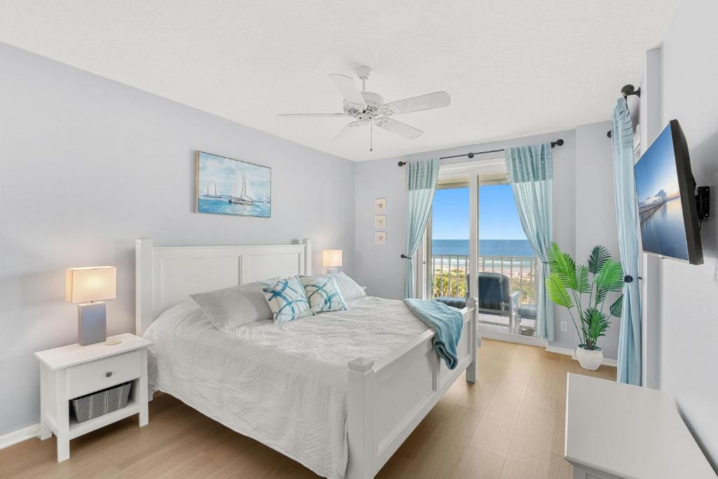 a white bedroom with a bed and a balcony at Ocean Oaks PHB-8 in Cape Canaveral