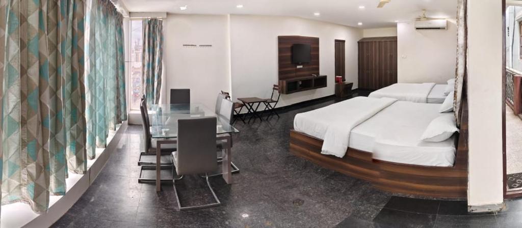 een slaapkamer met een groot bed, een tafel en een bureau bij 7Hills Residency in Anantapur