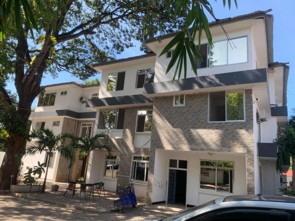 een groot wit huis met bomen ervoor bij Huasheng Hotel in Dar es Salaam