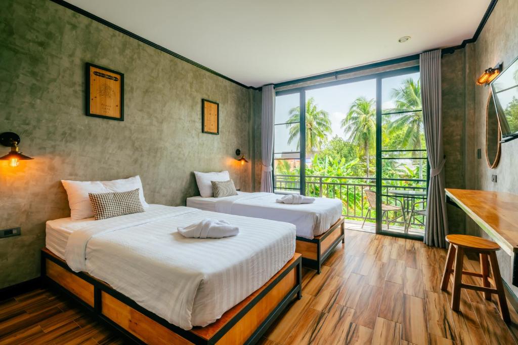two beds in a room with a large window at Lanta Chaolay in Ko Lanta