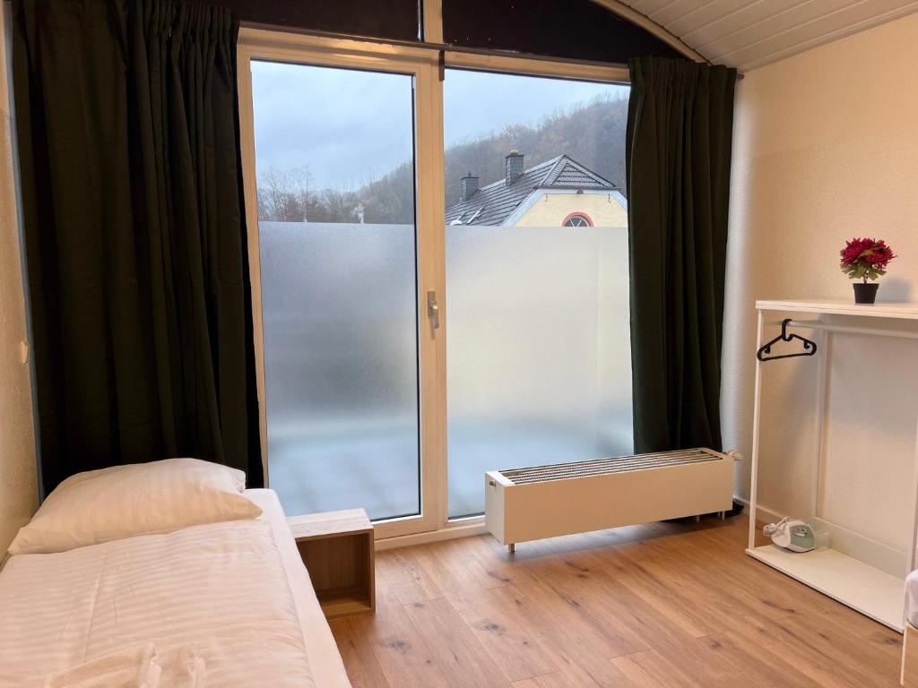 T&K Apartments - Comfortable 4 and 5 room Apartments - 20min Fair Messe CGN في أوفرات: غرفة نوم مع نافذة زجاجية كبيرة وسرير