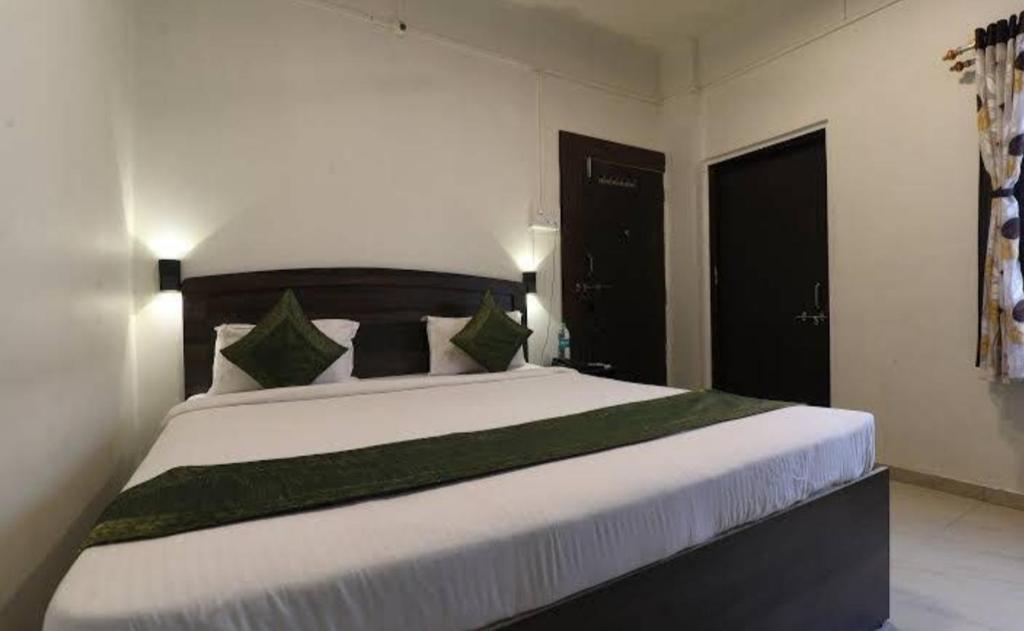 ein Schlafzimmer mit einem großen weißen Bett mit grünen Kissen in der Unterkunft Suman Lodging near Mahalaxmi Temple, Kolhapur in Kolhapur
