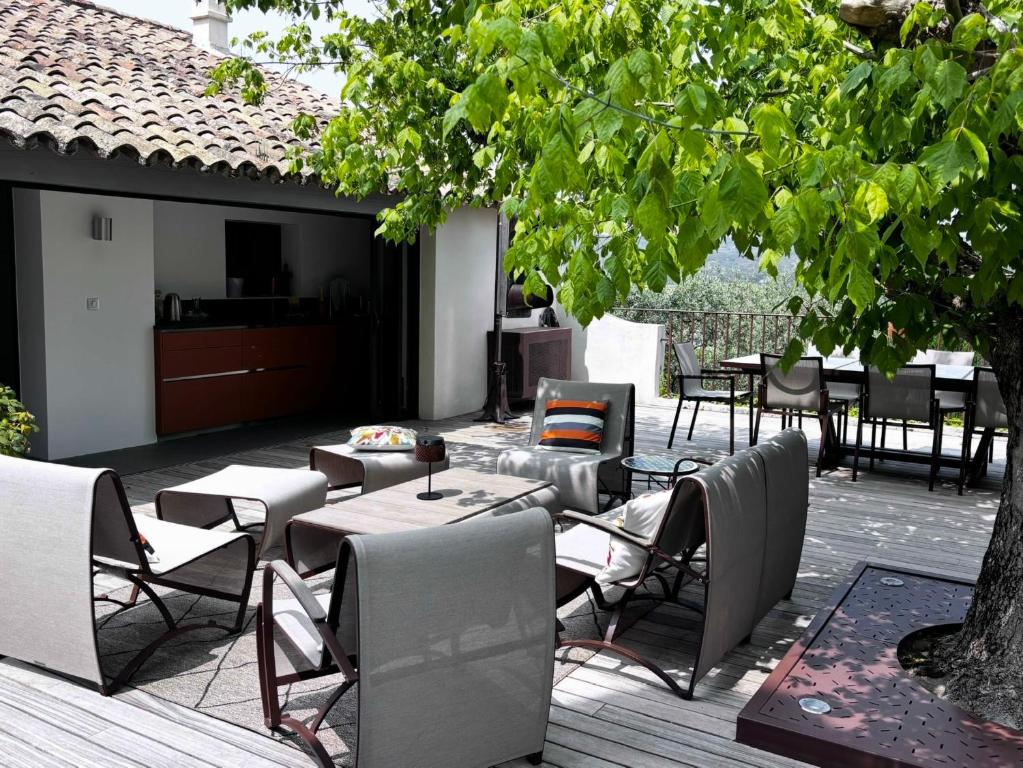 een terras met tafels en stoelen en een boom bij Maison V in Ventabren