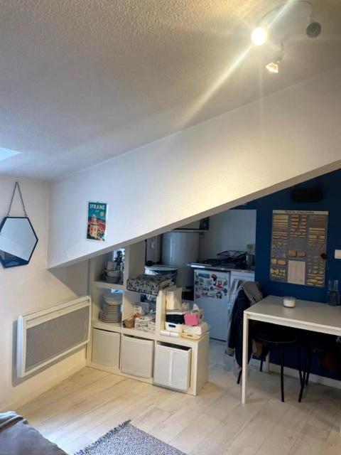 a room with a kitchen with a counter and a table at Studio cosy sous les toits en plein centre-ville in Clermont-Ferrand