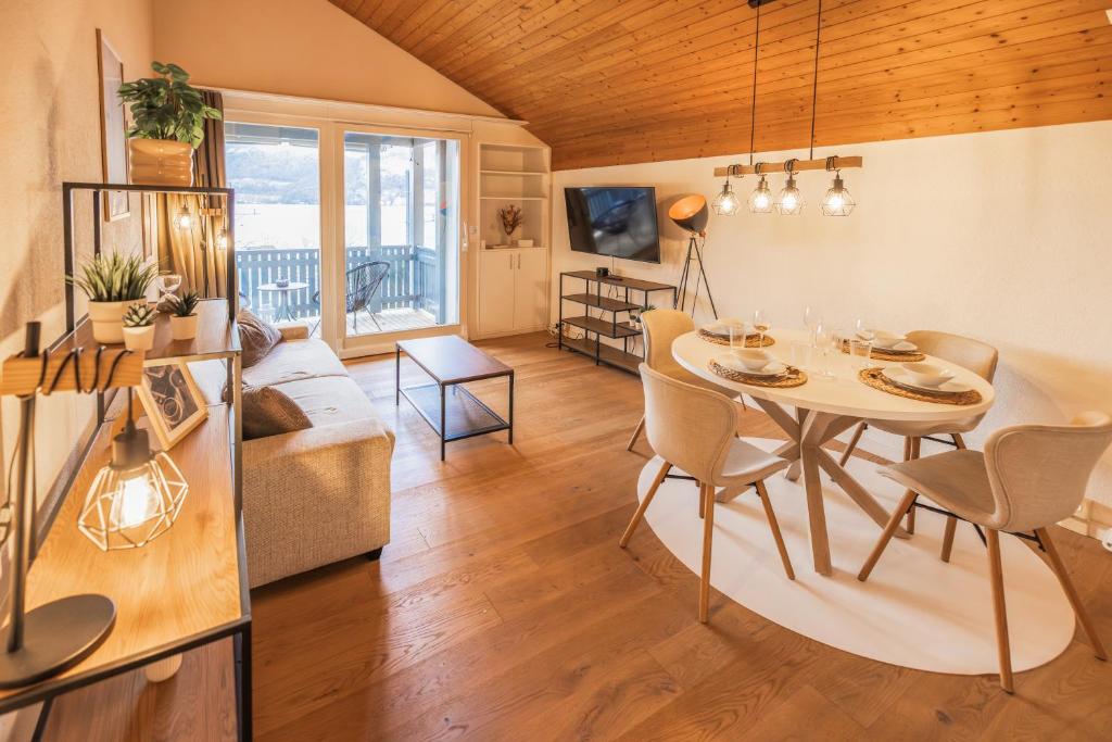 uma sala de jantar e sala de estar com mesa e cadeiras em Surfers Lodge near Interlaken, at lake with pool em Därligen
