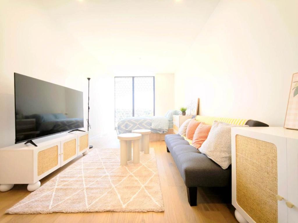 Box Hill Bright and Cozy Hotel Style One Bedroom Suite Kitchenette Ideal for Short Stays في بوكسهل: غرفة معيشة مع أريكة وتلفزيون بشاشة مسطحة