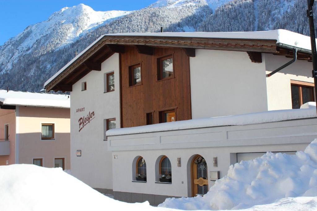 un edificio en la nieve con montañas en el fondo en Apart Pfeifer, en Ischgl