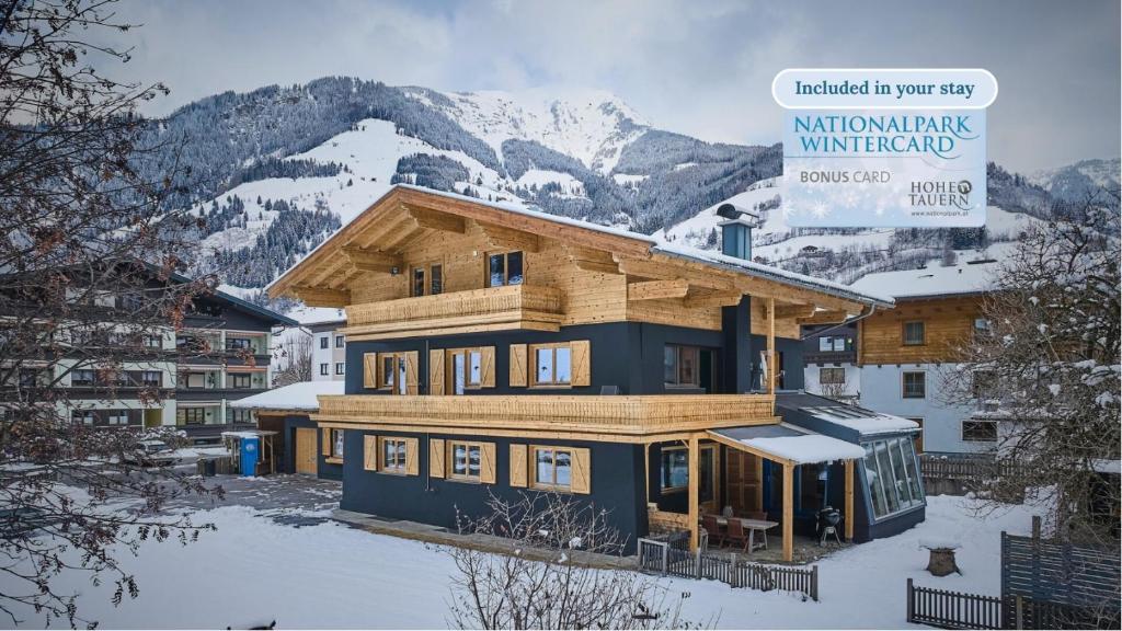 ein großes Holzhaus im Schnee vor einem Berg in der Unterkunft Apartments Enzian in Rauris