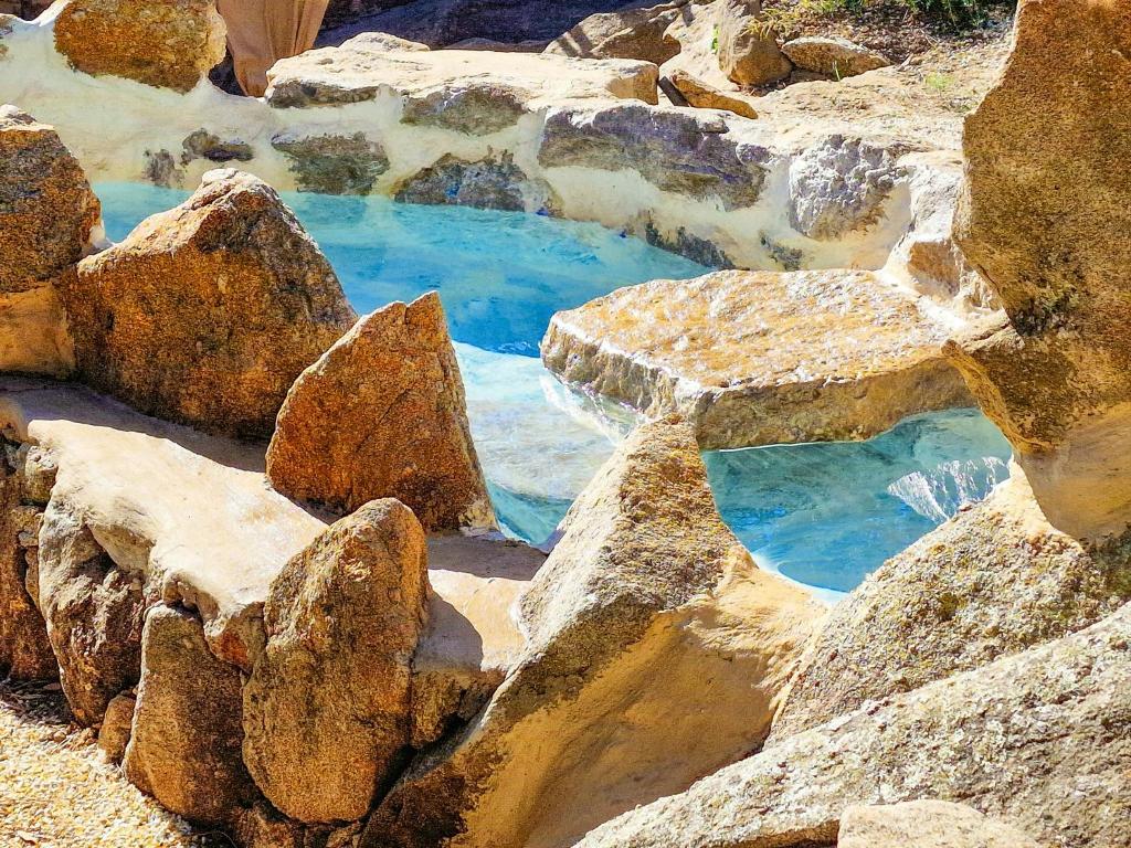 una piscina di acqua con rocce intorno di Sea View House Among Holm Oaks On Elba a Seccheto