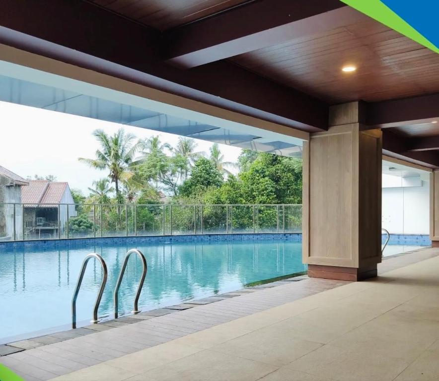 Apartemen Patraland Amarta Yogyakarta في Kejayan: مسبح وبجانبه كرسيين معدنيين