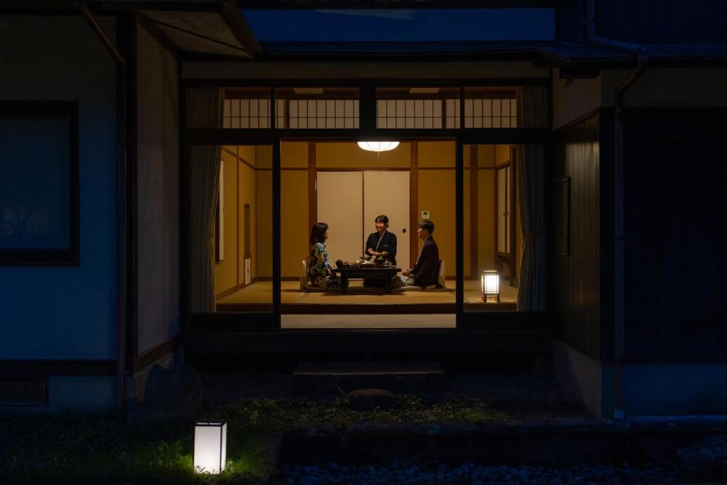 two people sitting in the window of a house at night at Tokiwa Bekkan in Toyooka