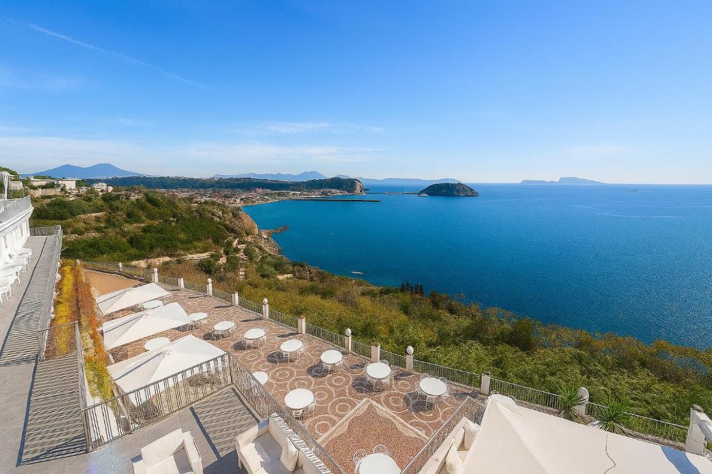 a view of the ocean from a building with tables and umbrellas at Hotiday Pozzuoli in Pozzuoli