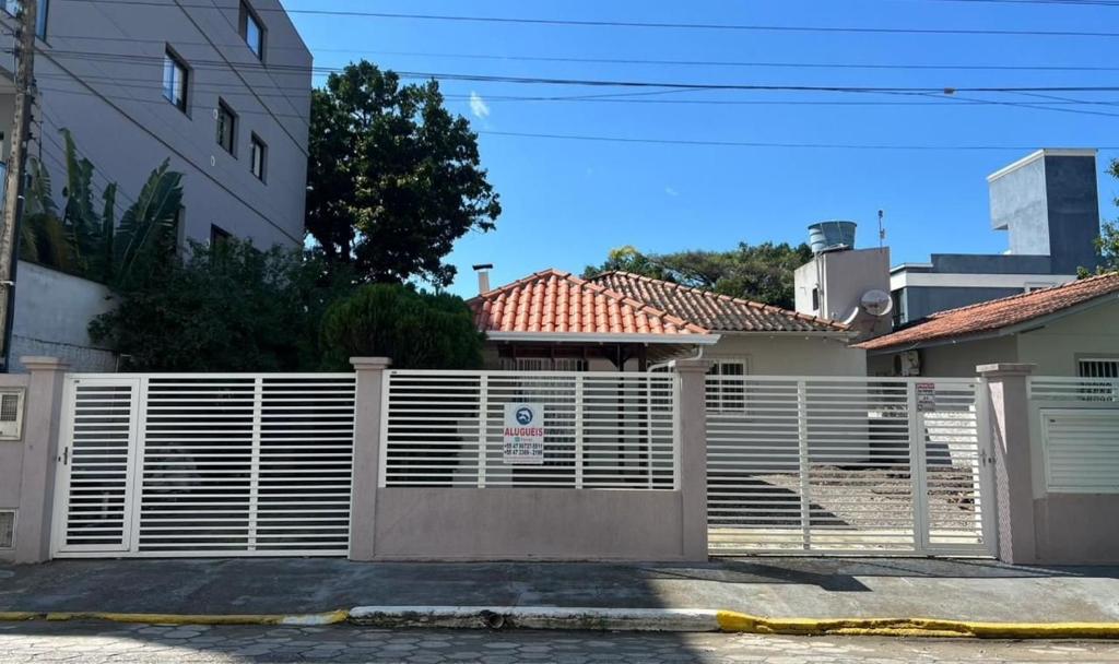 a white fence in front of a house at Residencial Elsa Tarcila in Bombinhas