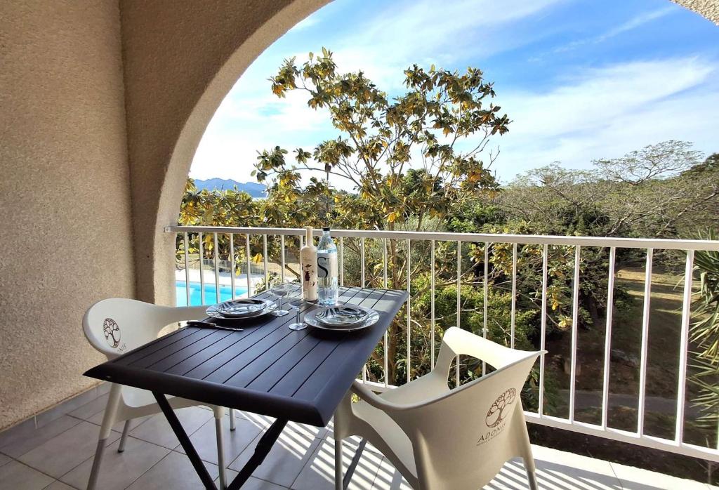 einen schwarzen Tisch und Stühle auf dem Balkon in der Unterkunft Studio ensoleillé à Saint-Florent avec piscine in Saint-Florent