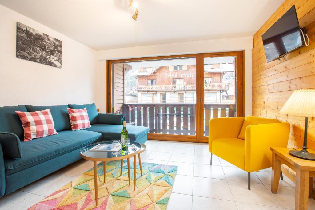 a living room with a blue couch and yellow chairs at Slalom Apartment - Very Town Centre - Snow and Trek - Morzine in Morzine