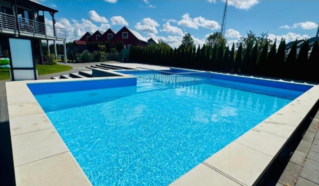 a swimming pool with blue water in a yard at Apartament Ksawery parking w cenie podgrzewany basen in Rewal